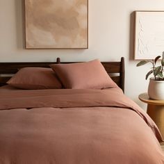 a bed with brown sheets and pillows next to a painting on the wall above it