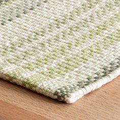 a close up view of a rug on a wooden floor with white and green colors