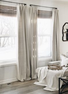 a living room filled with furniture and a window covered in white curtained drapes