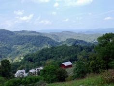 a mountain view with houses in the foreground and trees on the far side, surrounded by green hills