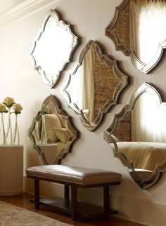 a living room with four mirrors on the wall and a bench in front of it