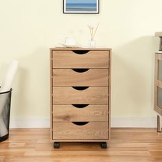 a wooden chest of drawers sitting on top of a hard wood floor next to a trash can