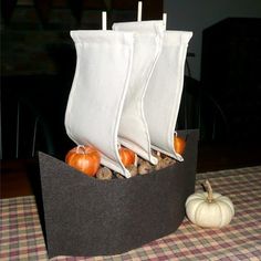 there is a boat made out of paper and pumpkins on the table with text that reads mayflower centerpiece