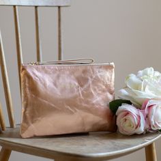 This rose gold clutch, is made with beautiful Italian metallic leather and lined with contrasting satin fabric in charcoal grey.  The Flora is a relaxed easy, everyday bag, great for dressing both up and down. It's the perfect companion when travelling light, ideal for holding purses, make-up and phones. It has a silver zip and matching loop leather pull. There's also a small, open, inside pocket.  It makes a great gift for a close family member or best friend and can be personalised with up to Elegant Gold Pouch For Everyday Use, Elegant Gold Pouch For Everyday, Chic Metallic Clutch Bag, Metallic Rectangular Clutch For Everyday Use, Rectangular Metallic Clutch For Everyday Use, Gold Cosmetic Bag With Removable Pouch, Rose Gold Bags For Everyday Use, Chic Gold Travel Pouch, Chic Rose Gold Bag