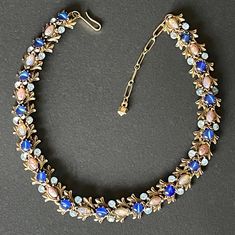 Gorgeous vintage gold tone collar necklace encrusted with glass stones. There are pale blue faceted rhinestones, blue satin / marbled glass round cabochons and lovely sparkly pink dragon's breath marquise cut glass cabochons. The style and the components are very like other collar and riviere necklaces attributed to the Sphinx company in the UK. The necklace has an adjustable length up to approximately 17 inches and can be shortened using the simple hook clasp and extension chain. It is in very Jeweled Costume Jewelry Necklaces For Evening, Costume Jewelry Jeweled Choker Necklace, Vintage Blue Choker Jewelry, Evening Cabochon Costume Jewelry, Evening Costume Jewelry With Cabochon, Vintage Blue Choker Necklace, Vintage Jeweled Choker Necklace, Metal Cabochon Necklace In Costume Jewelry Style, Vintage Blue Rhinestone Jewelry