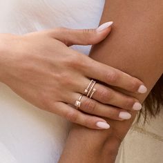 a woman's hand with two rings on her arm and the other hand holding another ring