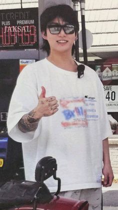 a man giving the thumbs up while standing in front of a gas pump