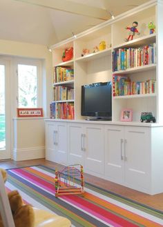 a living room filled with furniture and a flat screen tv on top of a book shelf