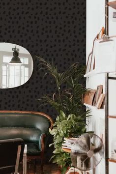 a living room with black and white wallpaper, green leather chair and potted plant