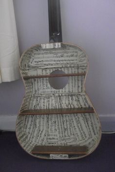 an old guitar with sheet music on it's back and sides is sitting in front of a window