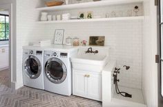 a washer and dryer in a white laundry room with open shelving on the wall