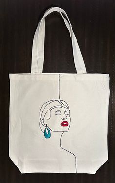 a white tote bag with a drawing of a woman's face on it