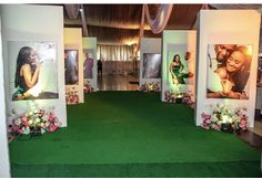 a room with pictures on the walls and flowers in front of it, along with green carpet