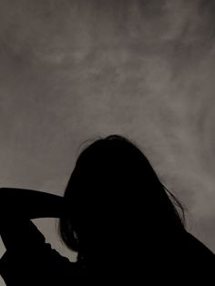 the silhouette of a woman holding her hair back