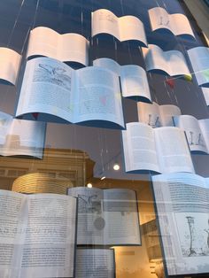 several open books hanging from the ceiling in a window