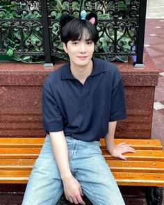 a young man sitting on top of a wooden bench