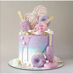 there is a cake decorated with pink and purple icing on the top, as well as lots of candies