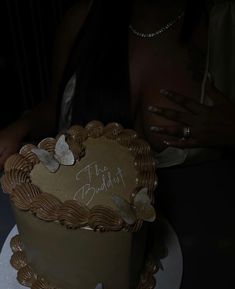 a heart shaped cake with writing on the top is sitting on a table next to a woman's hand