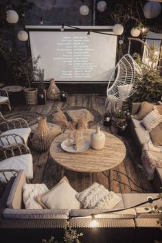 an outdoor seating area with wicker furniture and plants on the table, in front of a projector screen