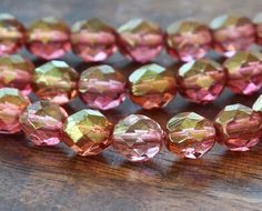 several pink and yellow beads on a wooden surface