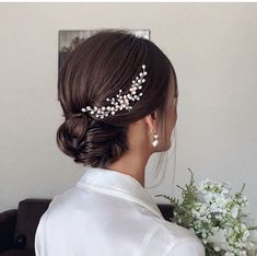 a woman wearing a hair comb with flowers in her hair and holding a white bouquet