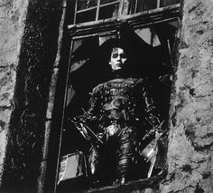 black and white photograph of a man sitting on a motorcycle in an old window sill