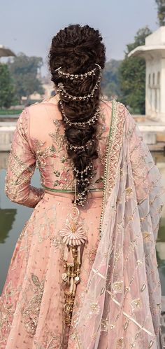 a woman with long hair wearing a pink lehenga