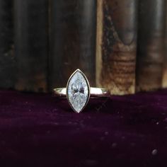 a white diamond ring sitting on top of a purple velvet covered table next to books