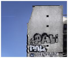 graffiti is spray painted on the side of a building in front of a clear blue sky