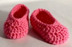 a pair of pink crocheted baby shoes sitting on top of a white surface