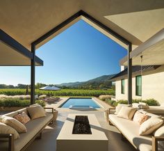 an outdoor living area with couches, tables and a fire pit in the middle