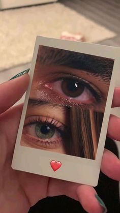 a woman holding up a polaroid with an image of her eye and heart on it