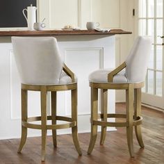 two white chairs sitting next to each other on a wooden floor in front of a counter