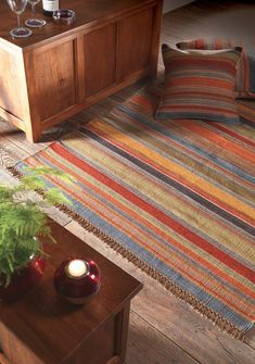 a living room with striped rugs and wooden furniture in the corner, along with two candles