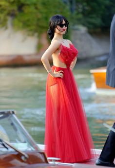 a woman in a red dress standing next to a boat