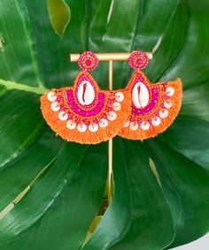 Introducing our "Finding Shells" Earrings in Orange/Fuchsia, a delightful addition to your summer accessory collection. These earrings feature small sea shells beautifully adorned with vibrant orange and fuchsia beads, creating a charming and beachy look. Crafted in a teardrop tassel style, they offer a playful and elegant aesthetic. With a secure post closure and measuring 2.75 inches, they are both stylish and comfortable to wear. Add a touch of seaside charm to your outfit with the "Finding Shells" Earrings in Orange/Fuchsia, perfect for embracing the spirit of summer! Handmade Pink Summer Jewelry, Bohemian Earrings For Summer Vacation, Pink Bohemian Beaded Earrings For Vacation, Summer Beach Drop Earrings, Handmade Earrings For Summer Vacation, Summer Party Beaded Earrings, Summer Beach Jewelry In Pink, Summer Beach Pink Jewelry, Multicolor Beaded Earrings For Summer Vacation