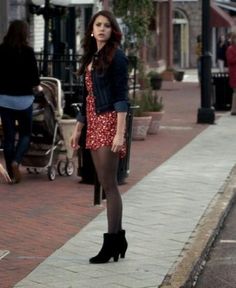 a woman is standing on the sidewalk with her legs crossed