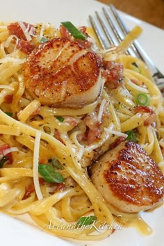 a white plate topped with pasta and scallops