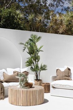 an outdoor living room with white furniture and plants