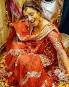 a woman sitting on top of a bed of flowers covered in yellow and red paint