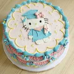 a hello kitty cake on a table with blue icing and pink fondant decorations