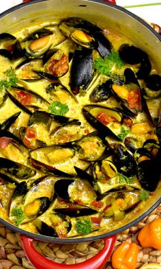 a pan filled with mussels and sauce on top of a table next to vegetables