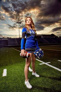 a cheerleader is posing on the field with her football glove and ball in hand