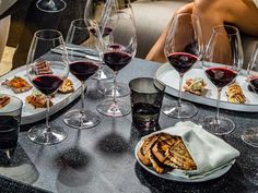 several glasses of wine are sitting on a table with plates of food and silverware