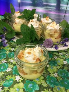 desserts in small glass bowls on a table with flowers and leaves around them, ready to be eaten