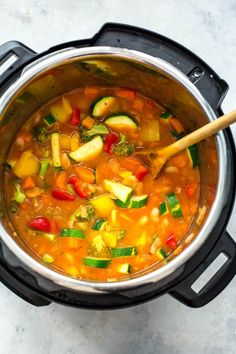 a pot full of vegetable soup with a wooden spoon