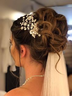 a woman in a wedding dress wearing a bridal hair comb with flowers on it