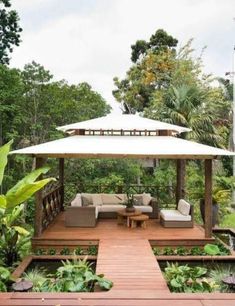 an outdoor living area with couches, tables and umbrellas in the middle of it