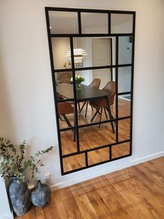 a dining room table and chairs are reflected in the mirror on the wall behind it