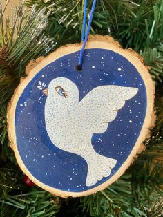 a wooden ornament with a white dove on it hanging from a christmas tree